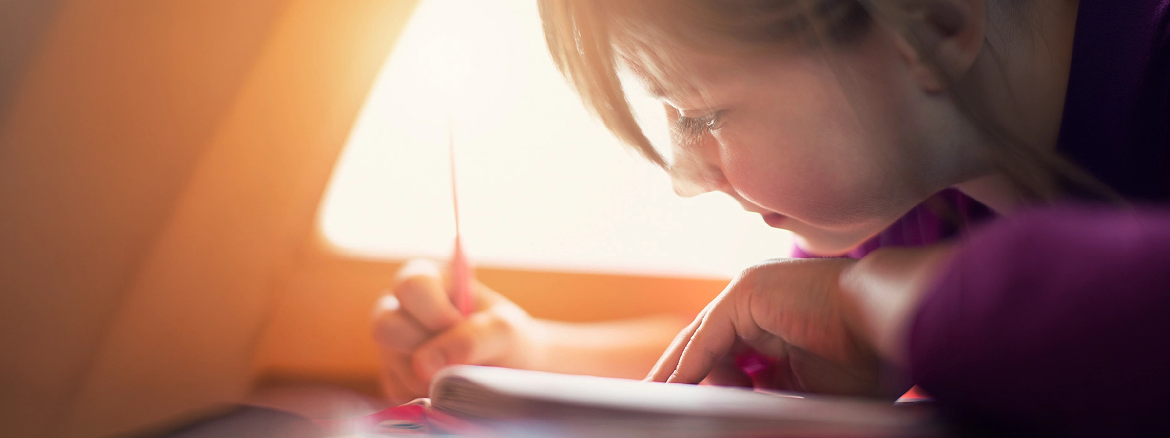 Child concentrating while writing in a notebook